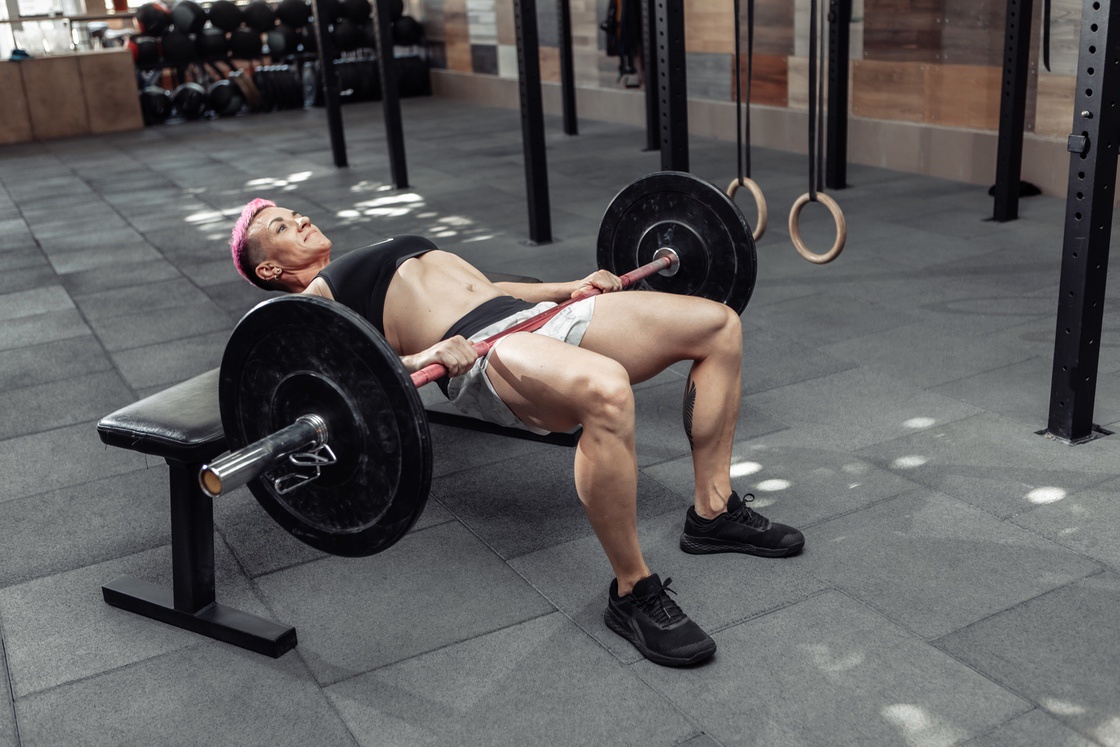Woman performing barbell glute bridge to build muscle
