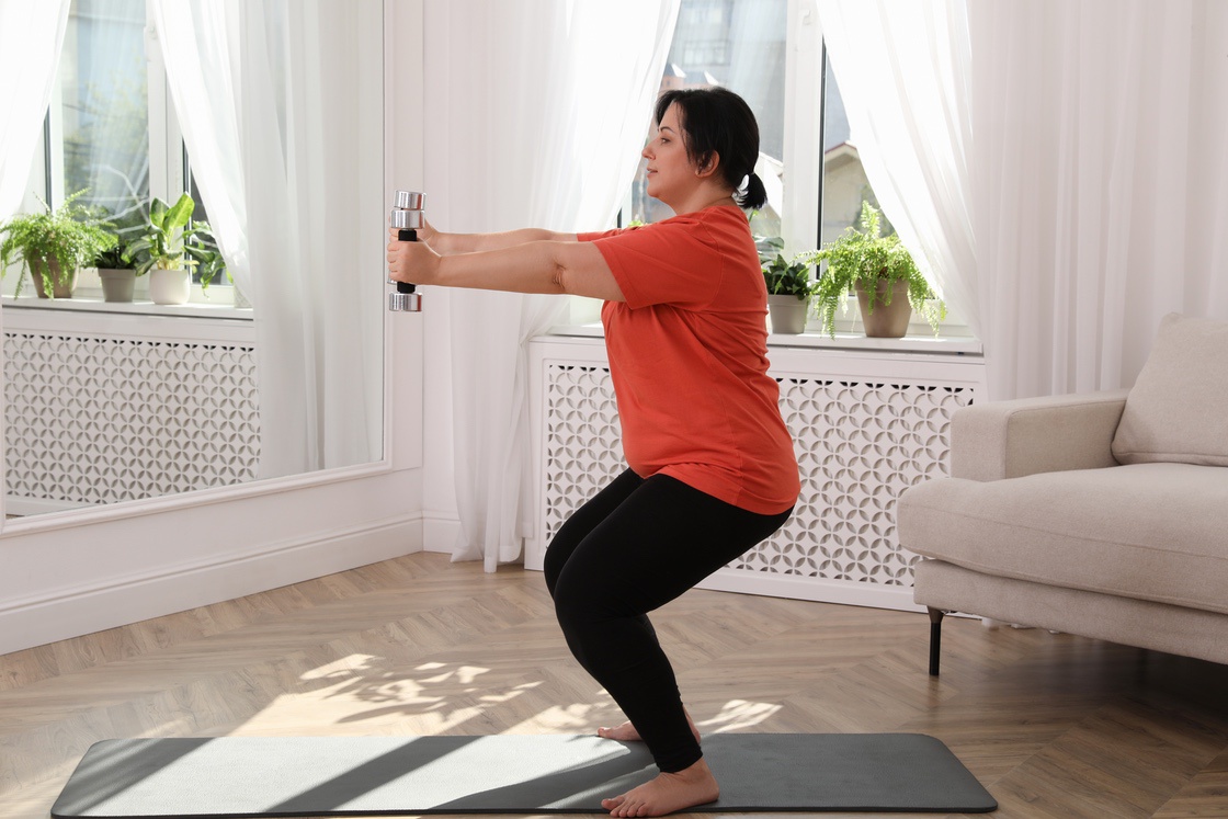 Woman doing goblet squat to burn fat during menopause
