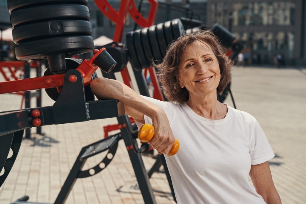 Smiling woman in menopause holding hand weights for resistance training