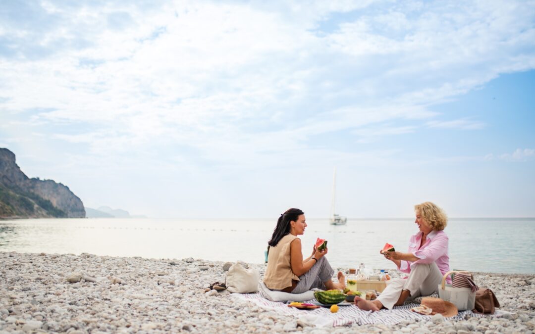 two women on the beach enjoying watermelon
