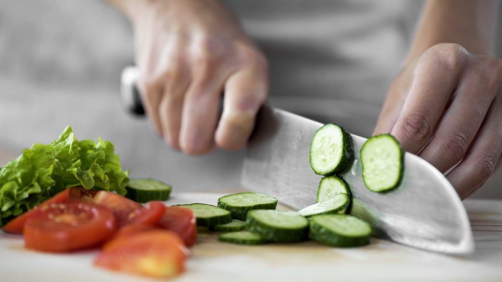 Person chopping raw vegetables as part of meal prep activities
