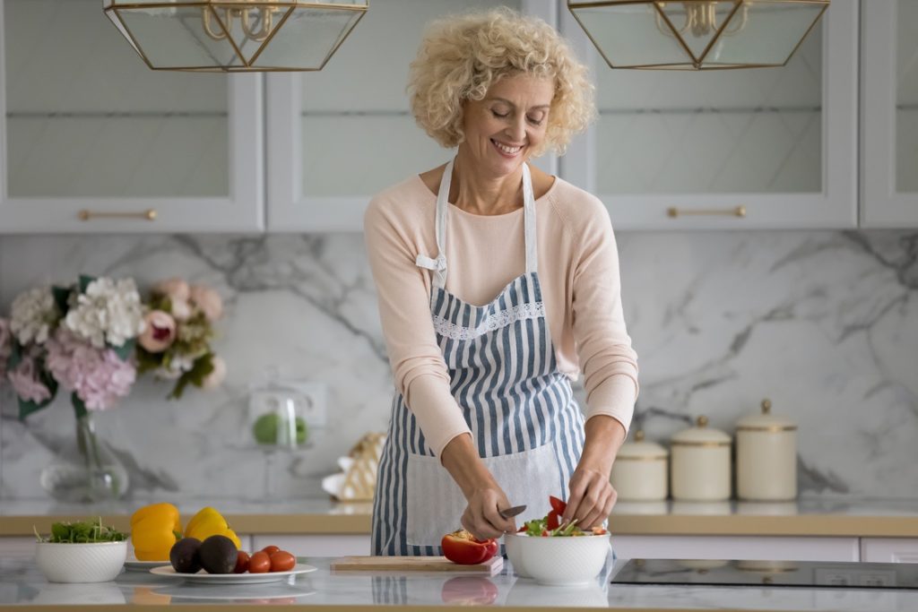Healthy mature woman smiling while meal prepping