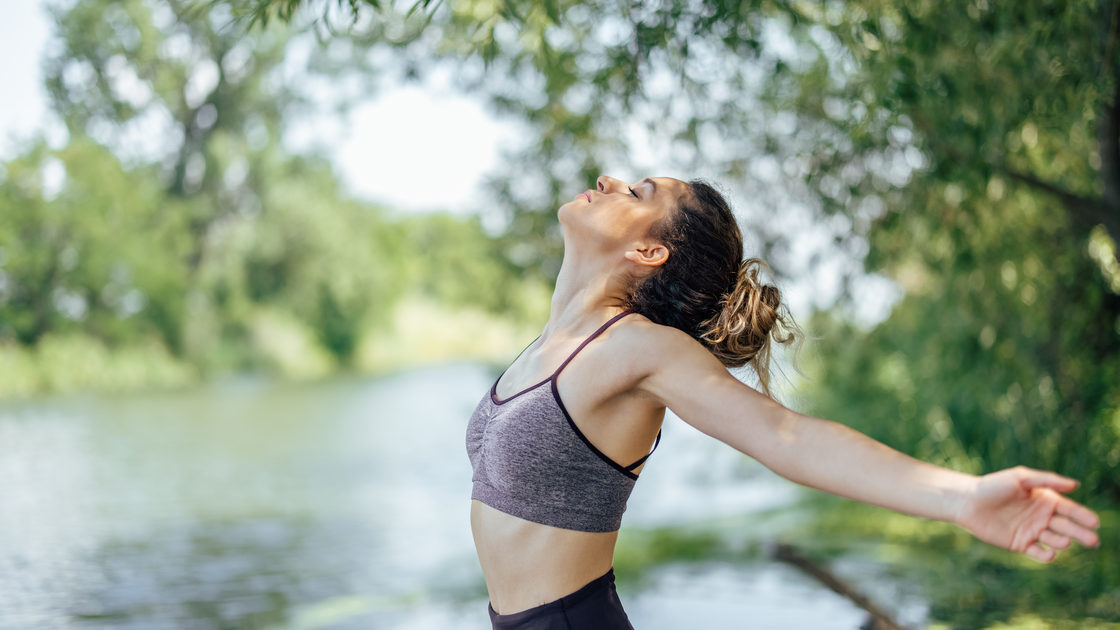 Woman in park with sports bra on releasing positive energy